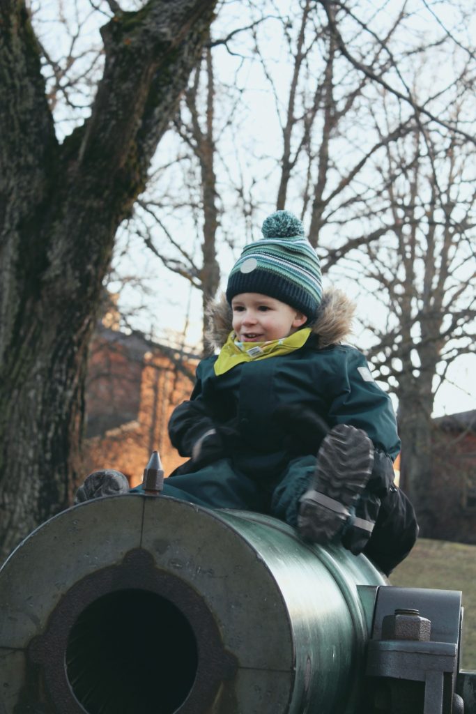 Lapsi Suomenlinnassa kanuunan päällä istumassa