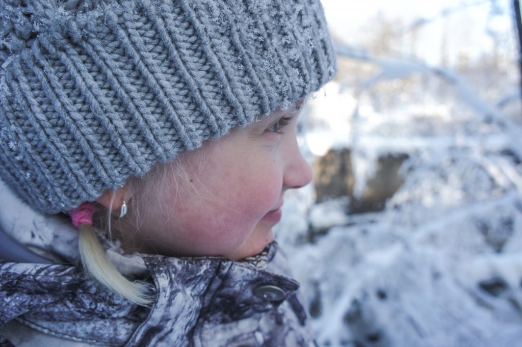 Sivukuva lapsen kasvoista talvimaisemassa, siniharmaat sävyt.