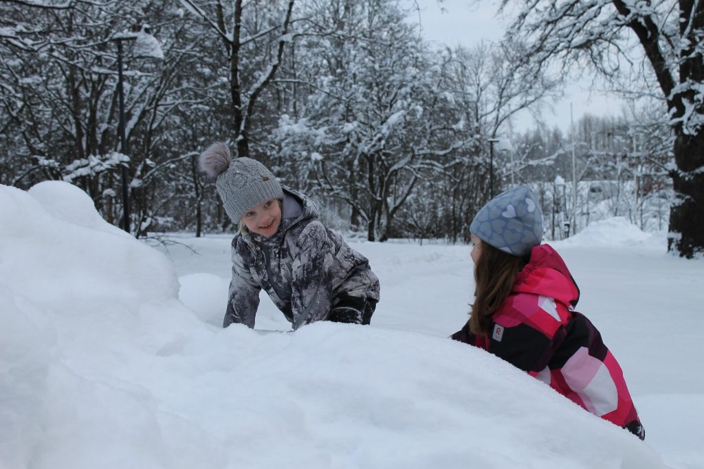 Kuvassa kaksi tyttöä leikkii lumessa