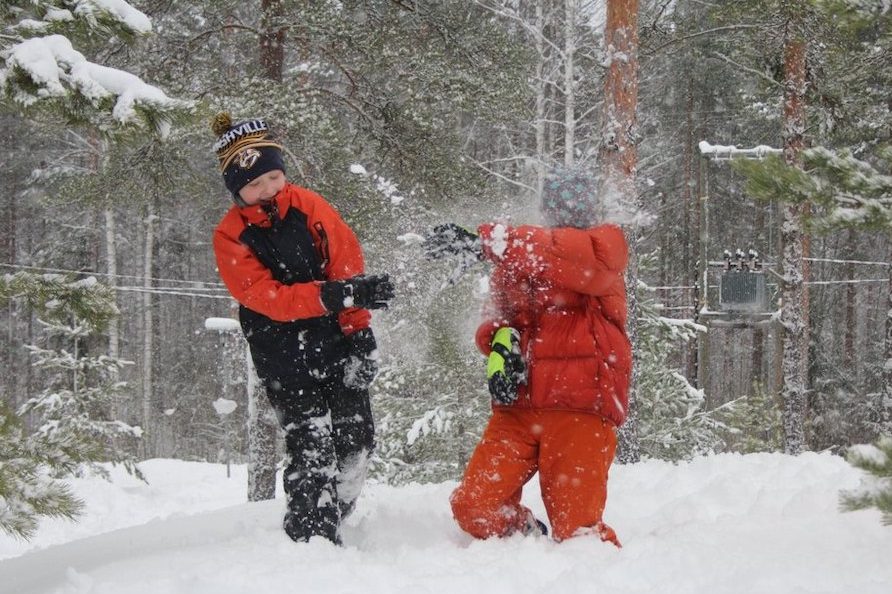 Kaksi poikaa leikkii lumessa ja heittelee lunta toisiaan kohti