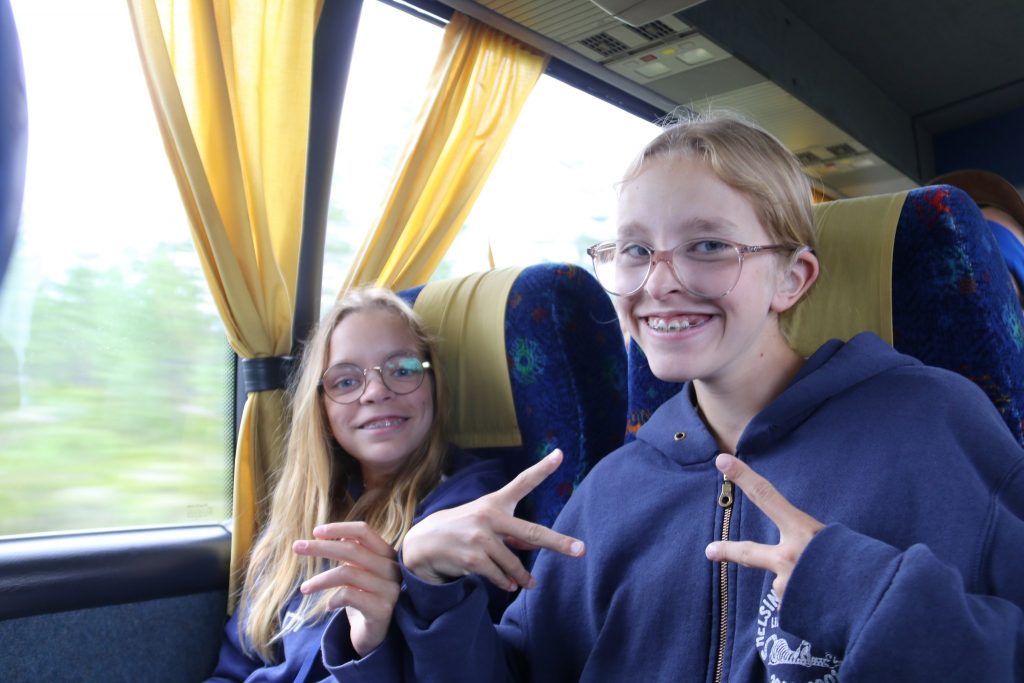 Kuvassa kaksi nuorta tyttöä poseeraa kameralle bussissa