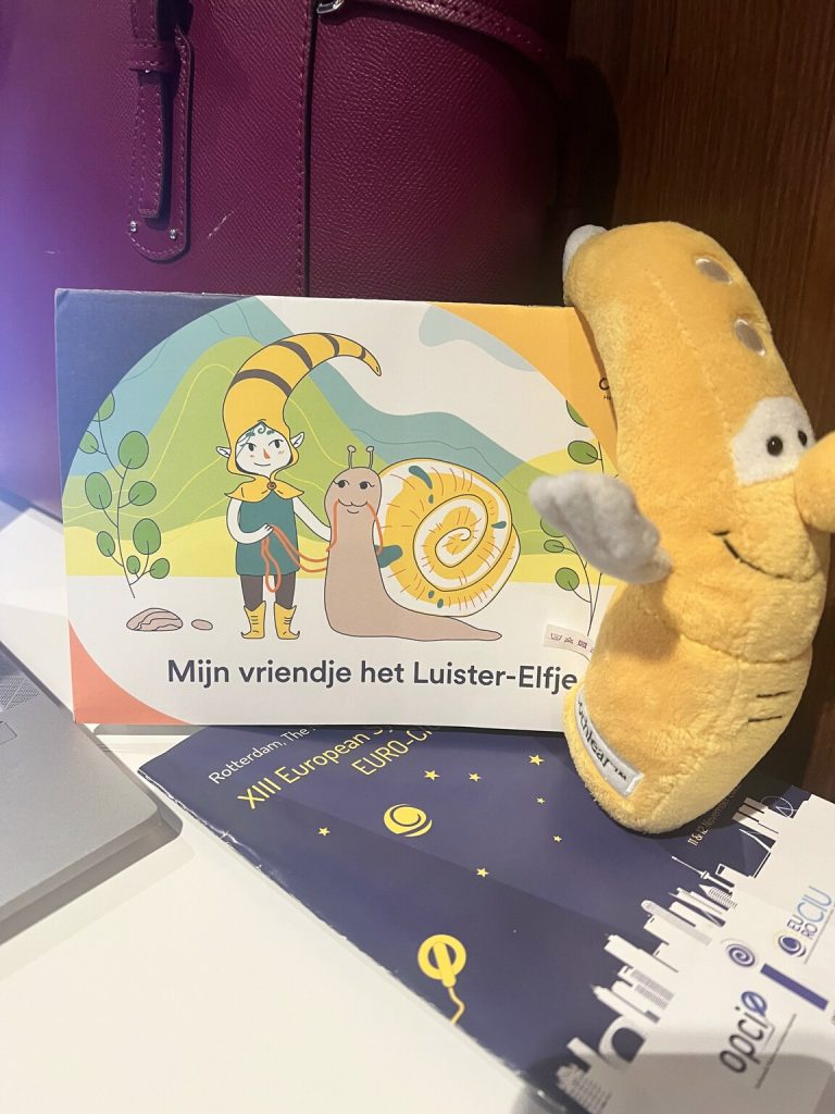 Kuvassa hollantilaisen SI-järjestön esite ja sen vieressä keltainen pehmolelu, joka esittää puheprosessoria