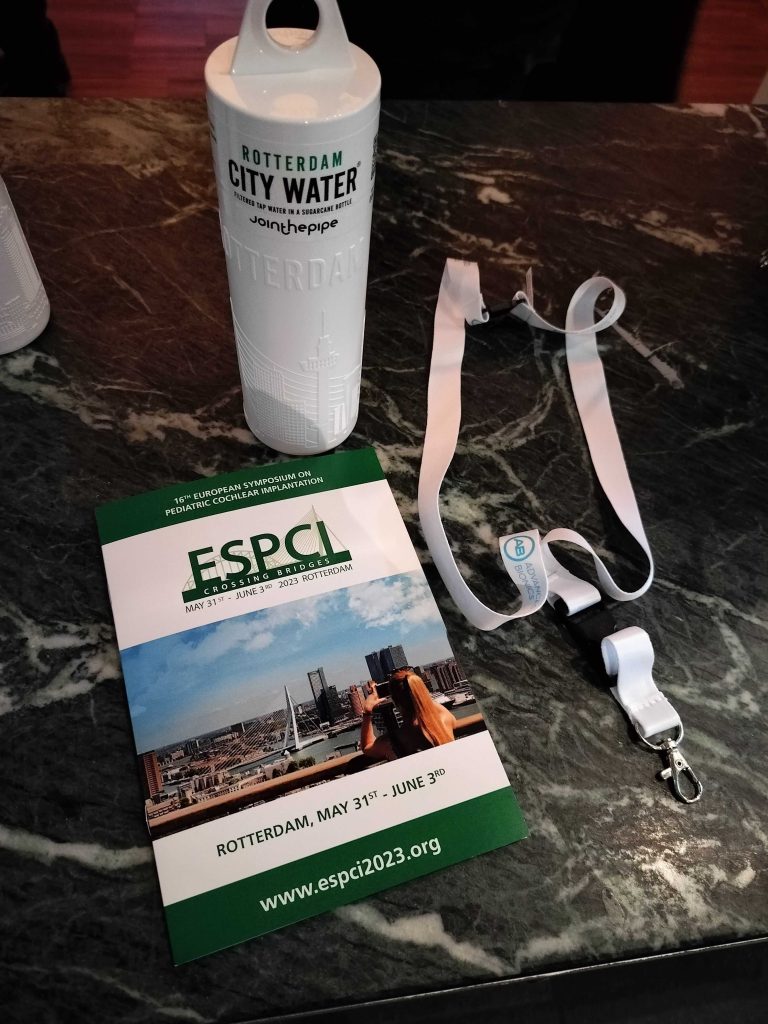 Kuvassa pöydällä ESPCI tapahtuman ohjelmavihkonen, kaula-avaimenperä ja valkoinen vesipullo.