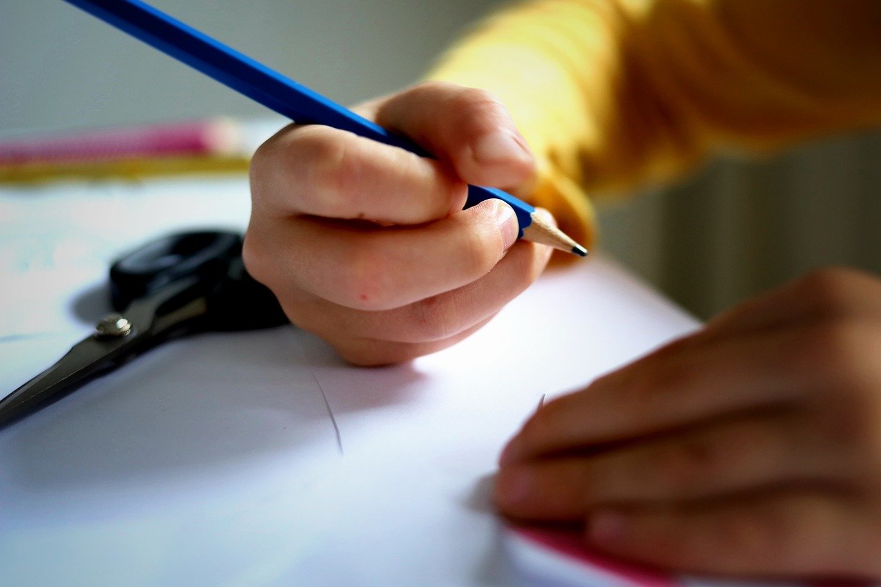 Lapsi pitelee kädessä kynää ja on aiekeissa kirjoittaa tyhjälle paperille.