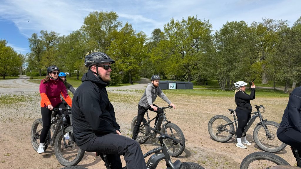 Vanhempien viikonlopun osallistujien fatbikejen selässä, he katsovat eteenpäin. Takana näkyy puistoa.