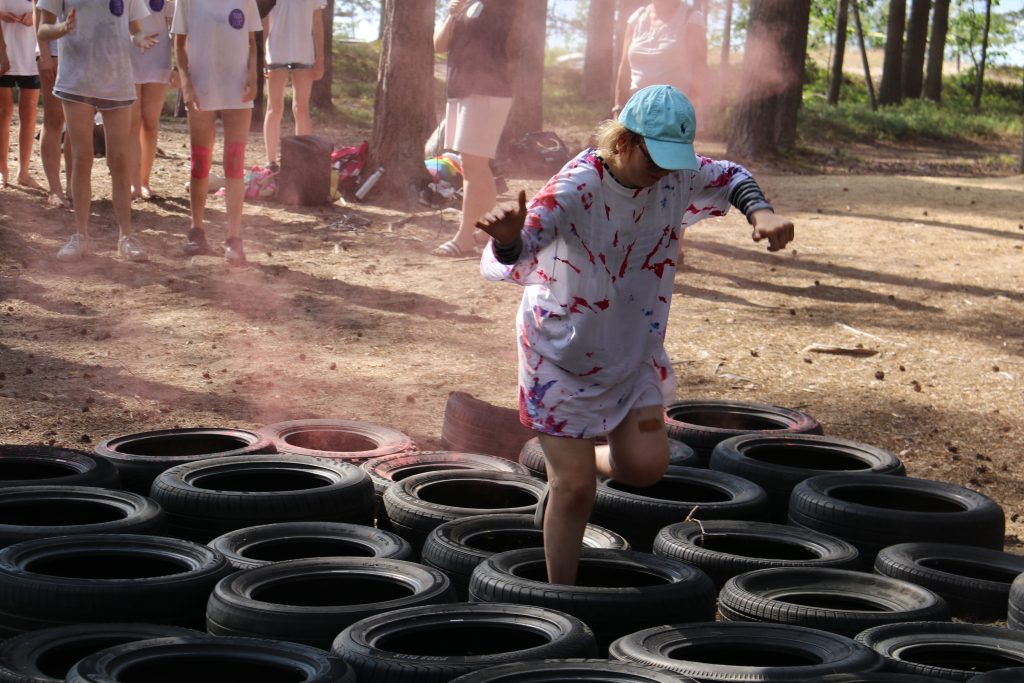 maassa mustia autonrenkaita, joiden päältä kävelee ihminen valkoisessa paidassa.