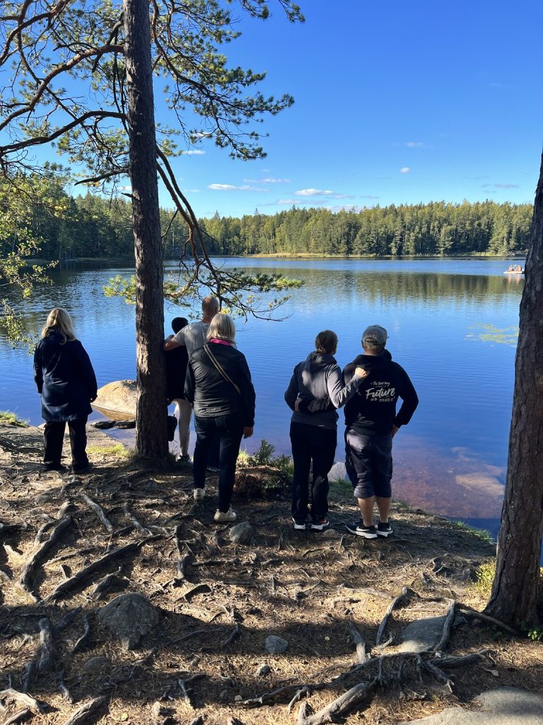 Vanhempia seisoon järven rannalla selät kameraa kohti.