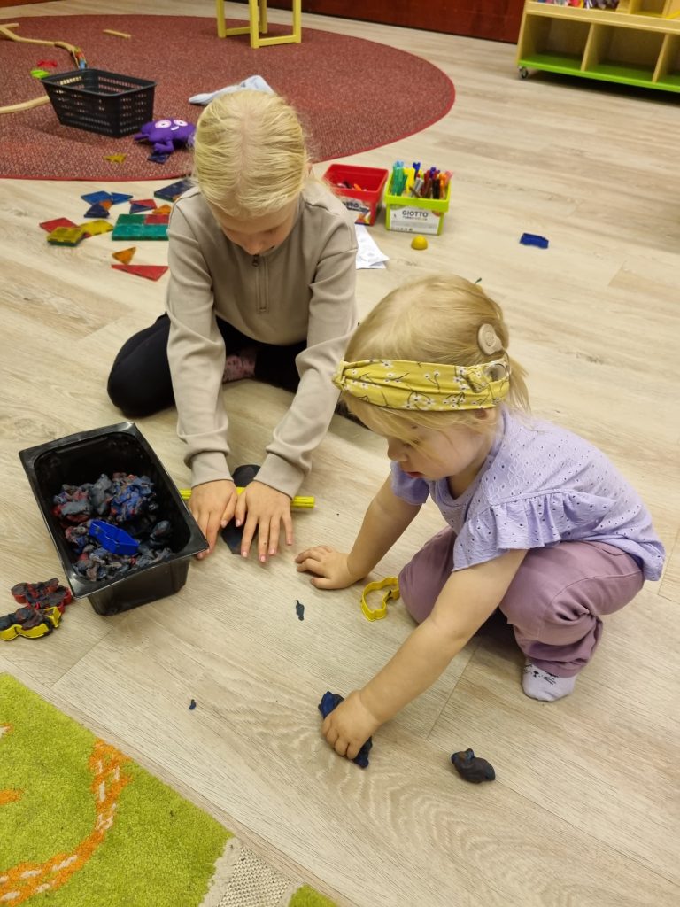 Kaksi lasta leikkii lattialla. Toisella on sisäkorvaistute.