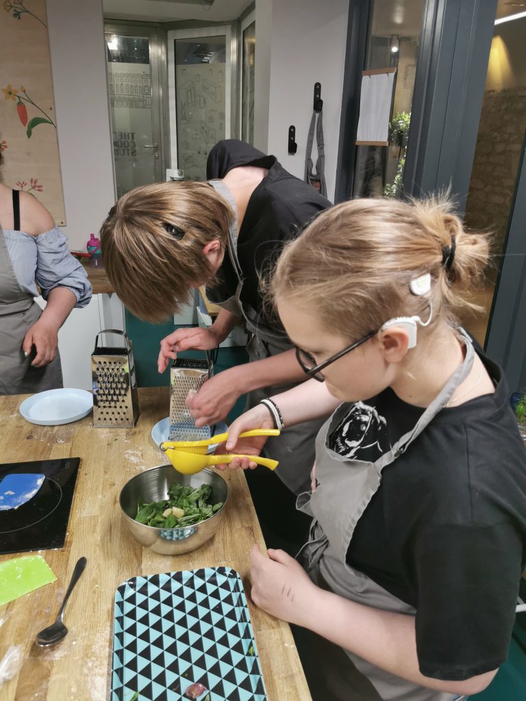 Kaksi nuorta tekemässä pestoa kokkaustunnilla. Nuorilla on sisäkorvaistutteet.